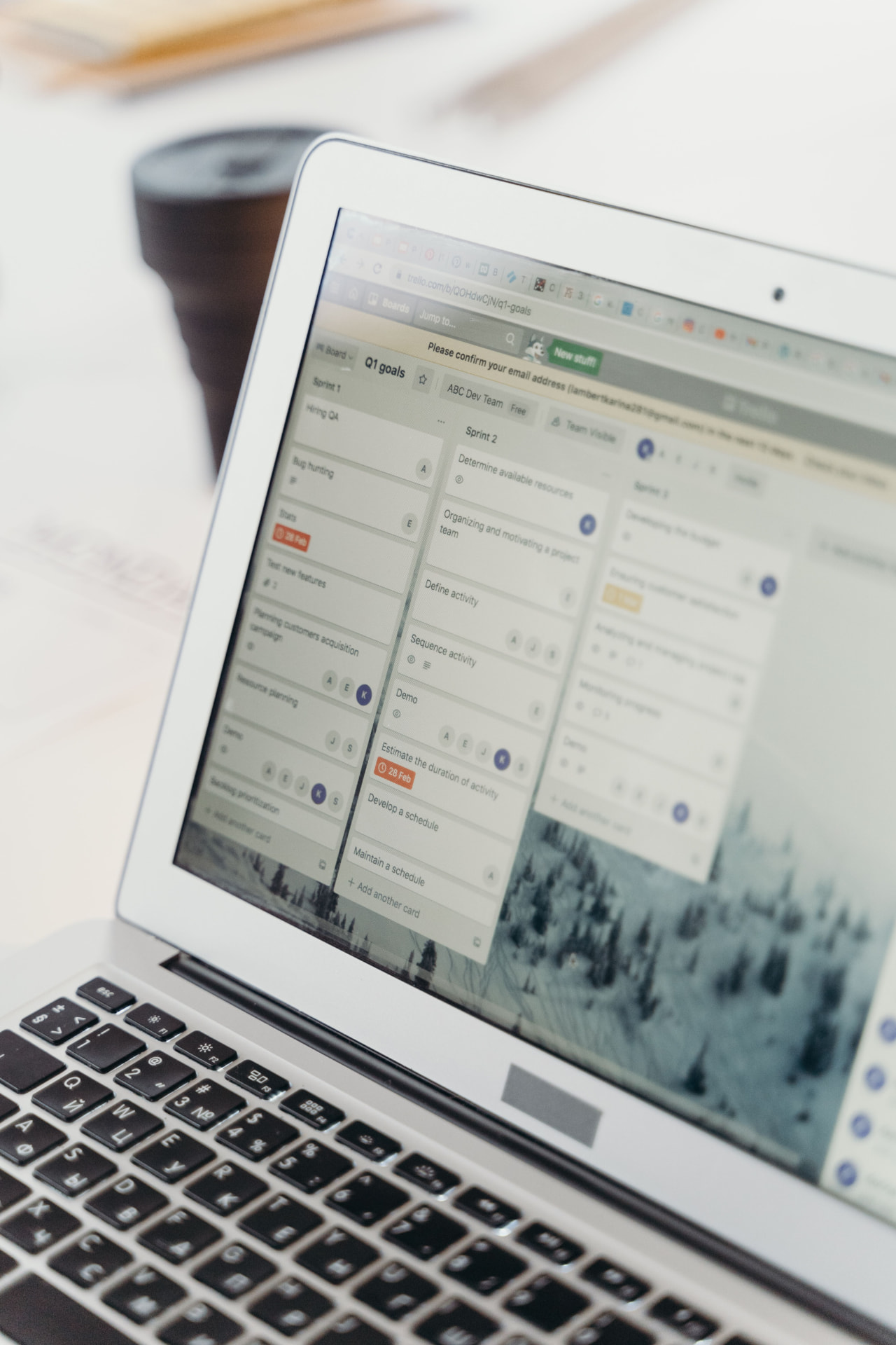 Laptop auf einem hellen Schreibtisch zeigt ein digitales Kanban-Board mit Sprint-Spalten und Aufgabenkarten